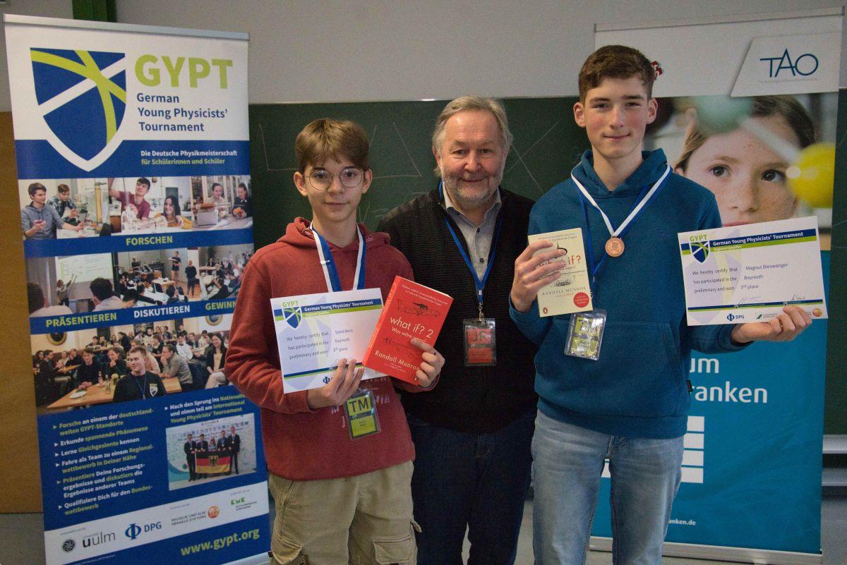 Danis Becic (links) und Magnus Bieswanger (rechts) bekamen die Bronzmedaille für ihr Team von Professor Walter Zimmermann von der Universität Bayreuth sowie eine Siegerurkunde und einen Buchpreis überreicht.